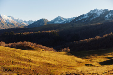 Autumn landscape of the nature of the mountains on a trip with snow-capped winter peaks in the background, off roads