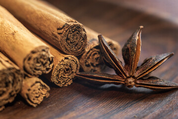Organic Raw Brown cinnamon sticks Anise star spice fruits and seeds on old wooden table wood stump trunk outdoor walnut plate spoon closeup macro Food Background Vintage Selective Focus.
