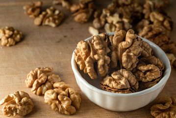 Fototapeta na wymiar bowl of Shelled walnut wooden table healthy food Close-up kernels and whole walnuts on rustic old.