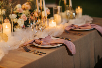 Beautiful table setting decorated with lighted candles, tableware, flowers, accessories for a...