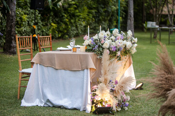 Beautiful table setting for bride and groom with tableware, flowers, candles, accessories and rose centerpiece for a party, wedding reception, gala banquet or other holiday event.