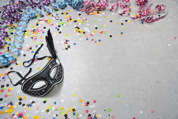Karnevalsmaske aus Venedig auf hellem Hintergrund mit bunten Konfetti und Luftschlangen
