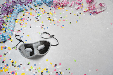 Faschingsmaske aus Venedig auf hellem Hintergrund mit buntem Konfetti und Luftschlangen