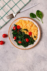 Cooked omelette and spinach with tomatoes on a light background