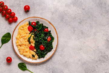 Cooked omelette and spinach with tomatoes on a light background