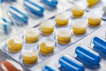 Heap of medical pills in white, blue and other colors. Pills in plastic package. Concept of healthcare and medicine.