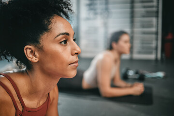 Black woman, gym focus and plank exercise of a person on the floor busy with workout and wellness. Sports, ground training and strength performance challenge of girl friends at a fitness health club