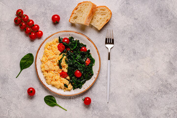 Cooked omelette and spinach with tomatoes on a light background