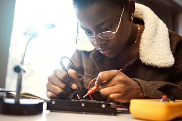University student, engineering and electronics with black woman learning on electrical project....