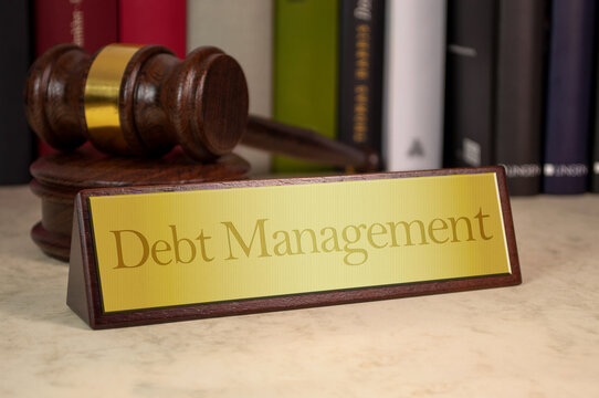 Golden sign with gavel on a desk with message debt management