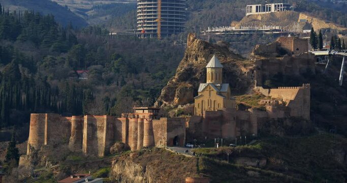 Church of St. Nicholas the Wonderworker on territory of Narikala fortress on the rocks of Sololak hill, wooded hills in background, cable car, Narikala fortress