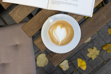 Cup of coffee and a book in a street cafe on an autumn morning