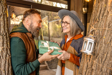 Smiling man giving a gift to his wife and looking happy