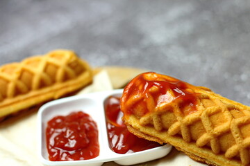 Corn dogs waffle and ketchup on a gray table