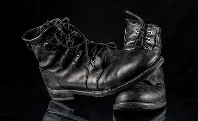 A pair of worn men's leather boots on a black background.