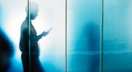 Glass wall, email and businessman reading on a phone for contact, communication and work. Silhouette, social media and employee typing on a mobile chat with news, information and app for work