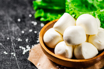 Mozzarella cheese in a wooden plate with lettuce. 