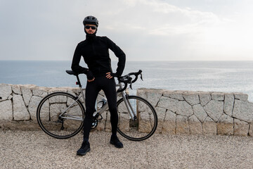 cycling composition. a man in a cycling suit stands next to a bicycle on a serpentine against the backdrop of rocks. person riding a bicycle