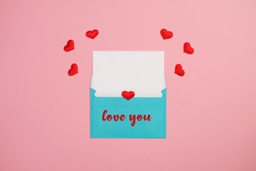 Valentine's Day holiday card. Red small cloth hearts and empty card with blue envelope on pink background. Valentines day concept.  Greeting hand made quote 