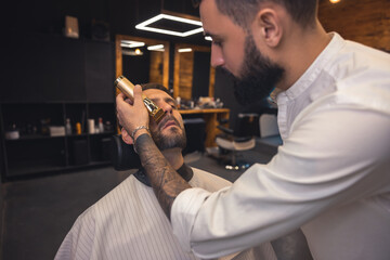 Barber in the salon working on the clients beard