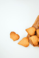 Shortbread cookies in the form of hearts in a brown paper bag on a white table. Top view