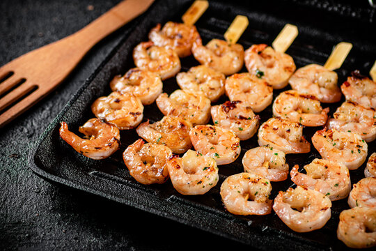 Shrimp on skewers are grilled in a grill pan. 