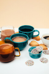Mugs of coffee with foam and a plate with heart-shaped shortbread cookies on a white background. Front view