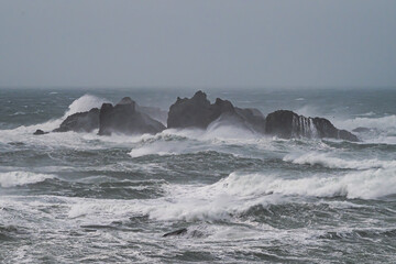 Waves crash on rocks in ocean during storm.