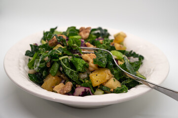 Delicious green Tuscan kale salad on white background. 