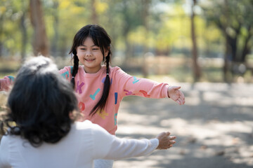 Happy young girl and her grandmother hugging in the public park, having a great itme