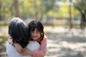 Happy young girl and her grandmother hugging in the public park, having a great itme