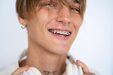 Portrait stylish blonde short haired woman with facial piercing and dental braces looking at camera and smiling against white background. - obrazy, fototapety, plakaty