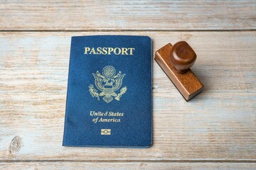 US passport and stamp on wooden background. Safe journey with necessary documentation. Top view....
