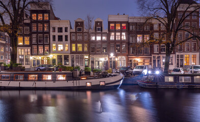 Beautiful old houses on the city waterfront of Amsterdam at sunset.