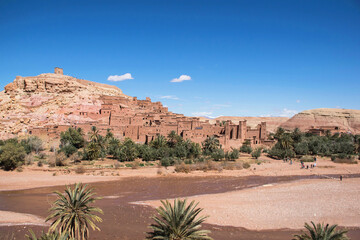 Fototapeta na wymiar Village ait ben haddou, Morocco. Desert landscape with oasis and atlas mountains on the background. Traditional build houses. High view point with scenic landscape. 