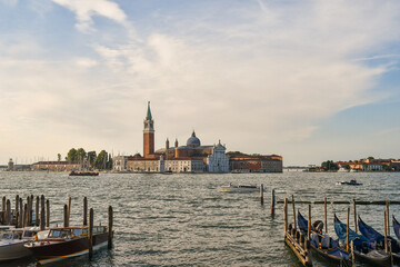 View of the island of San Giorgio Maggiore from Riva degli Schiavoni waterfront with docked gondolas in the foreground at sunset, Venice, Italy