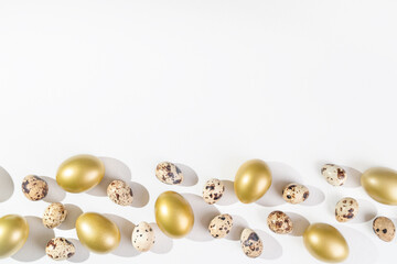 Eggs painted golden and quail eggs on white background. Minimal Easter concept.  Natural farm products. Frame with place for text
