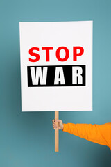 Woman holding poster with words Stop War on light blue background, closeup