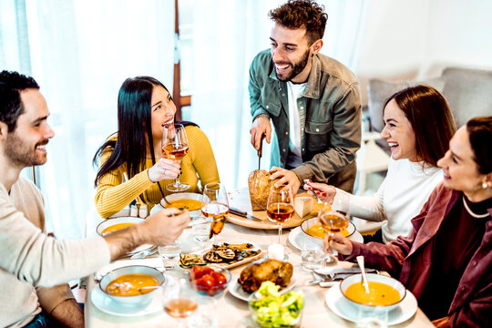 Man cutting bread - Smiling friends are having a dinner party at home - People laughing while eating soup - Friendship life style concept with young people having fun together at restaurant