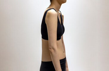 Side view of woman's round shoulders in black sportswear