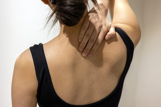 Woman puts her hand on neck and shoulder in black sportswear