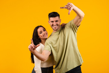 Happy millennial arabic husband and wife make hands lens, look through foreshortening