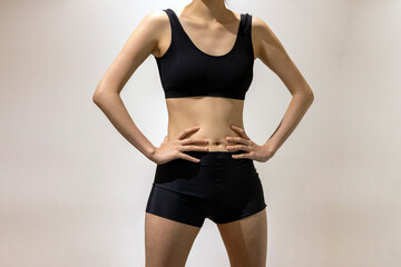 Fototapeta na wymiar Hands on the waist, Front view of slim fit woman's body in black sportswear