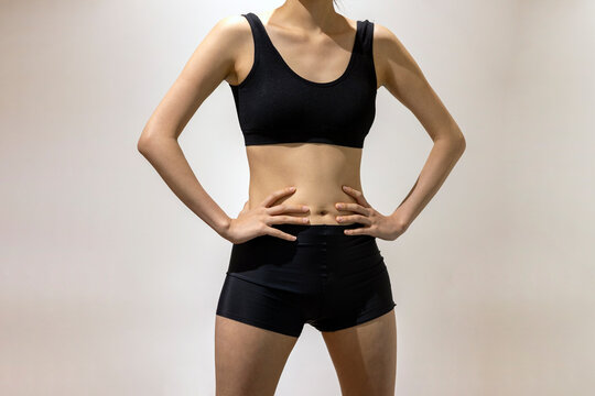 Hands on the waist, Front view of slim fit woman's body in black sportswear