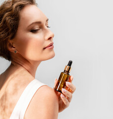 Beautiful elegant woman  holding a cosmetic jar of oil serum or hyaluronic acid in her hand