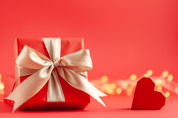 Red gift box and red heart on red background. Creative greeting card for Saint Valentine day.