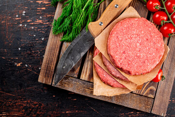 Raw burger on a wooden tray with tomatoes and dill. 