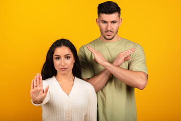 Serious strict millennial arab guy and woman in casual make stop sign and cross arms