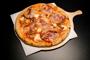 view on round pizza with bacon on wooden chopping board