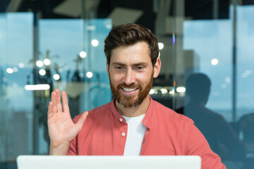 Video call of successful and cheerful smiling businessman, man talking remotely using laptop while...
